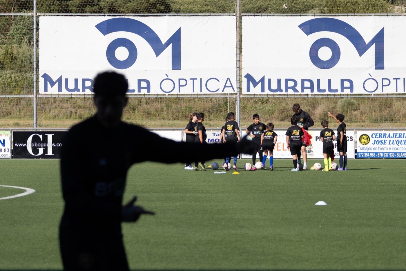 Entrenador de Blanda Elite Academy dando indicaciones a un grupo de jugadores en el campo
