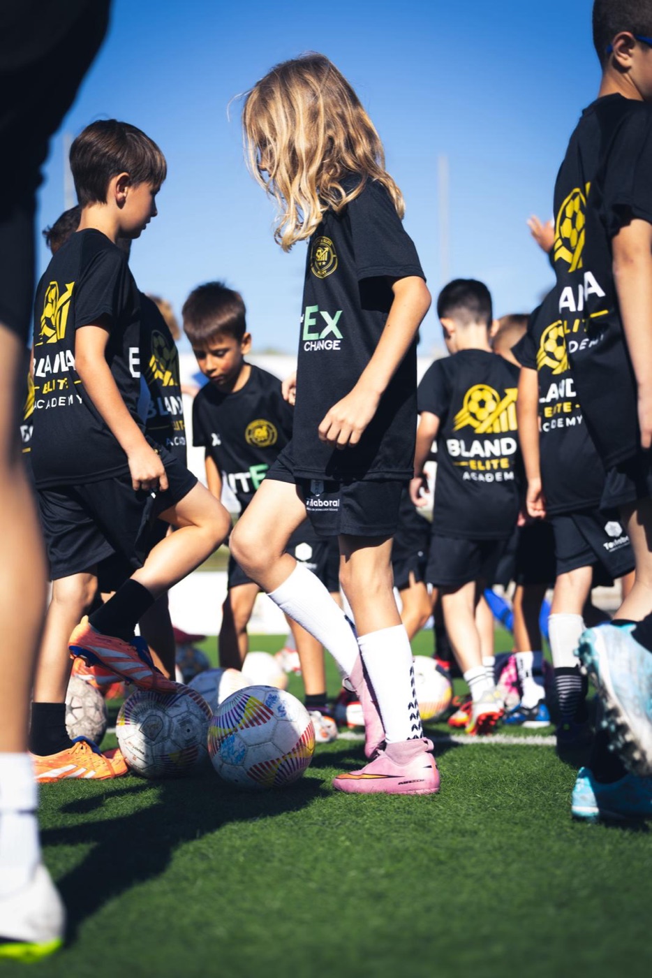 Jugadores de Blanda con la camiseta de la academia trabajando con balón