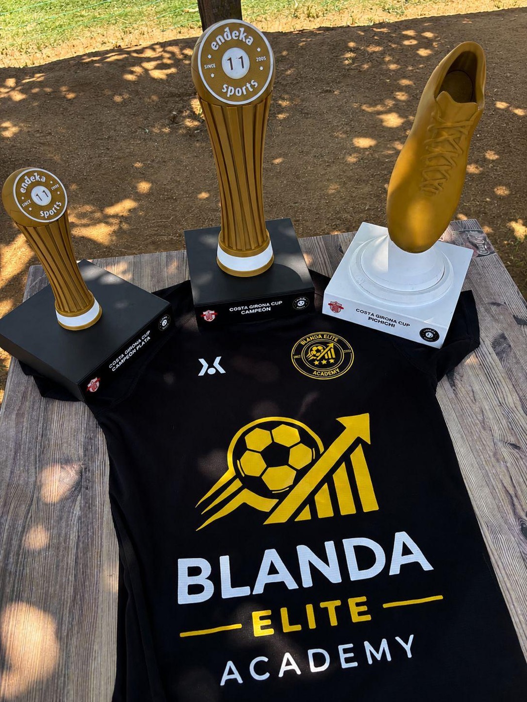 Trofeos de la Costa Girona Cup: campeón, campeón plata y pichichi, junto a la camiseta de Blanda